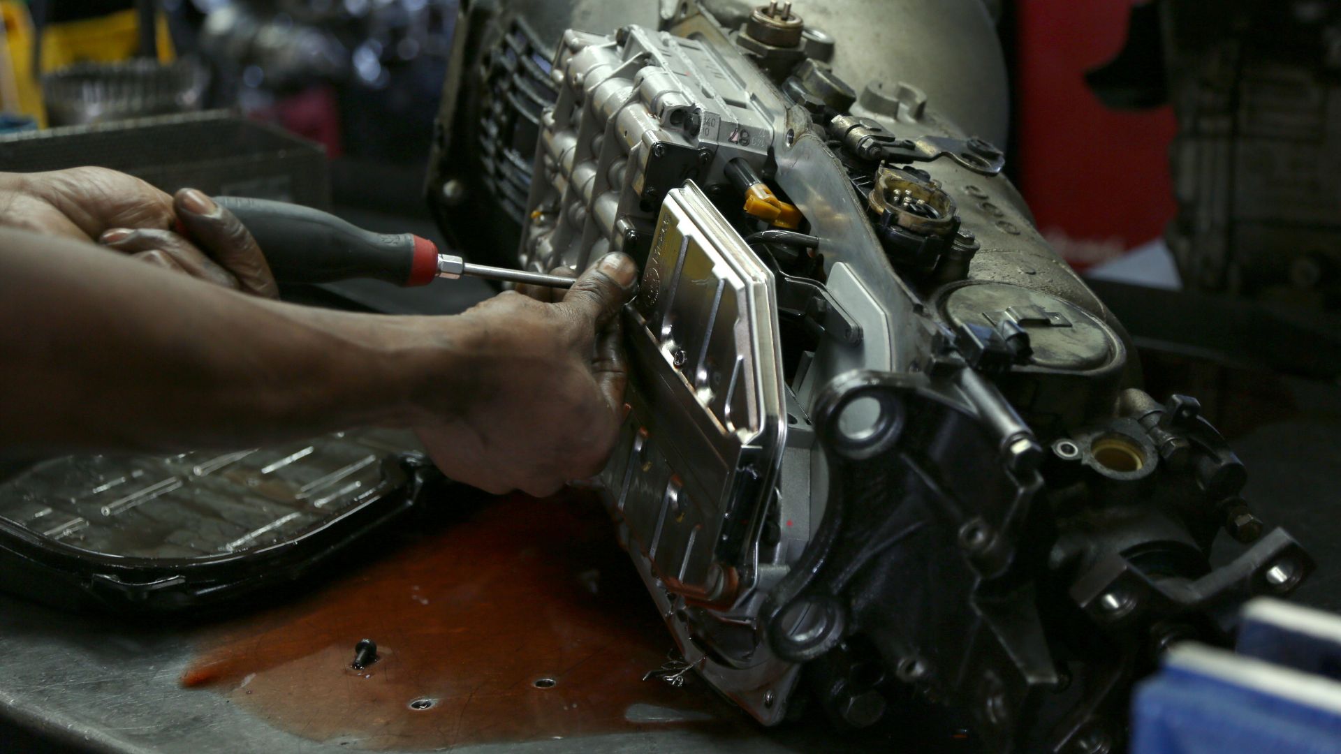 Mechanic's hand using screwdriver to repair complex metallic engine component