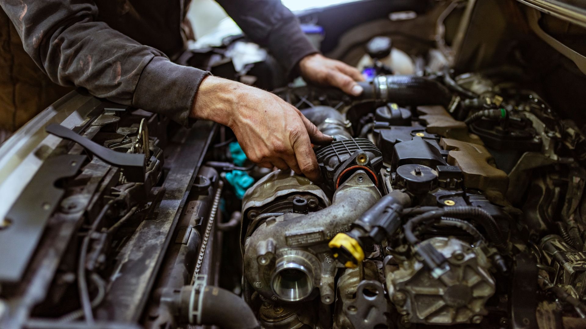 Mechanic repairing car engine with hands working on complex machinery
